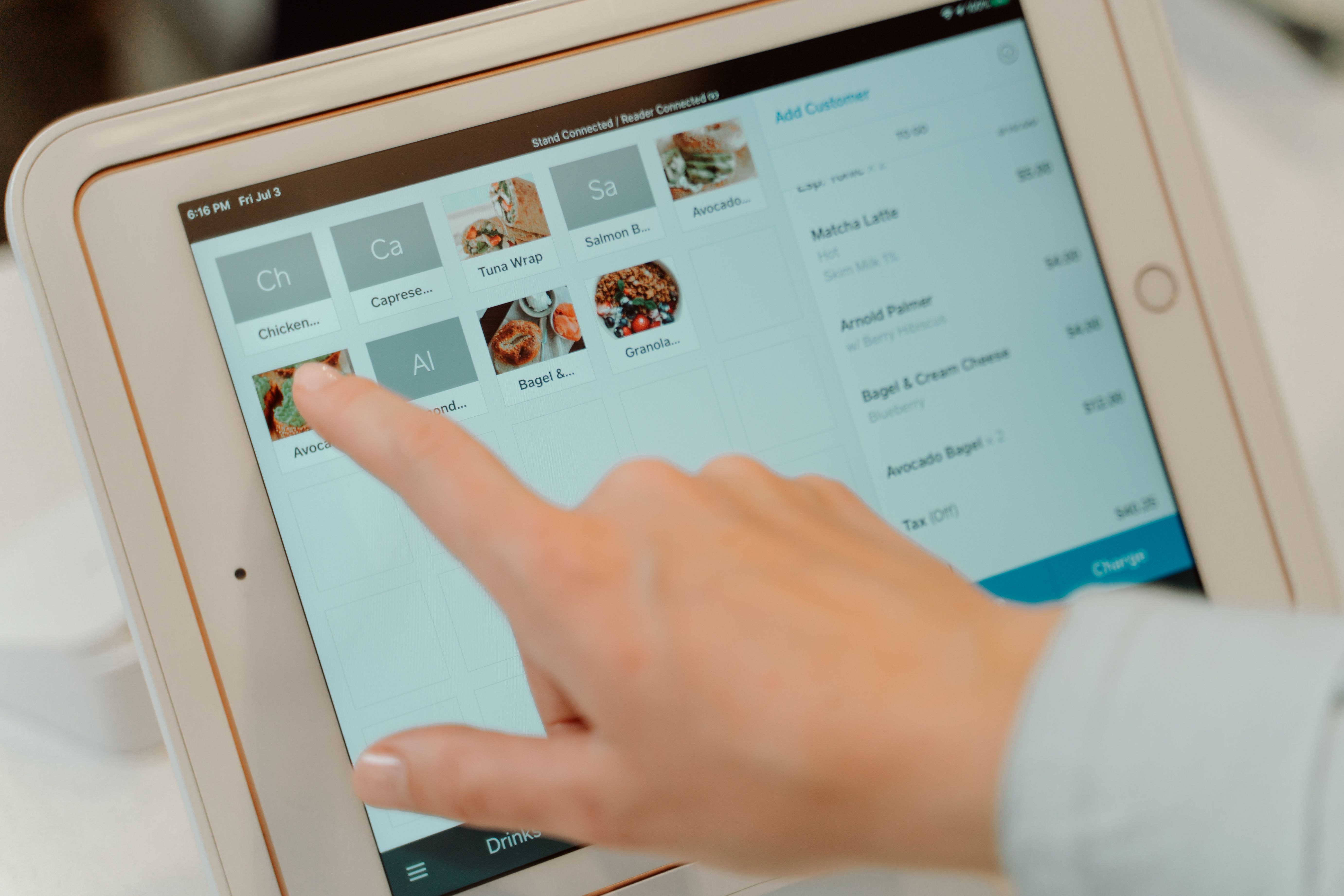 A customer tapping a tablet to select food items in a restaurant ordering system.